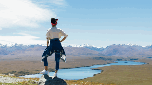 Woman looking out from a cliff top at a mountain range in New Zealand. Nationwide personal loans available at Instant Finance